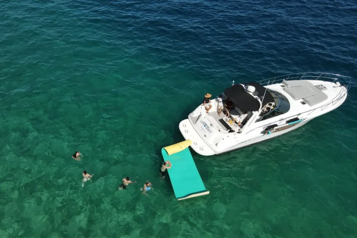 Swimmers and a floating mat beside the Sundancer