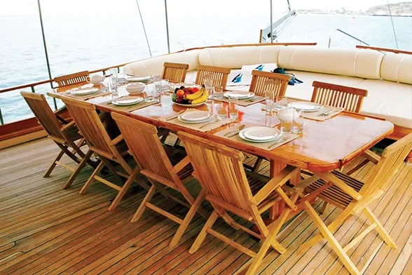 Long teak dining table set on deck